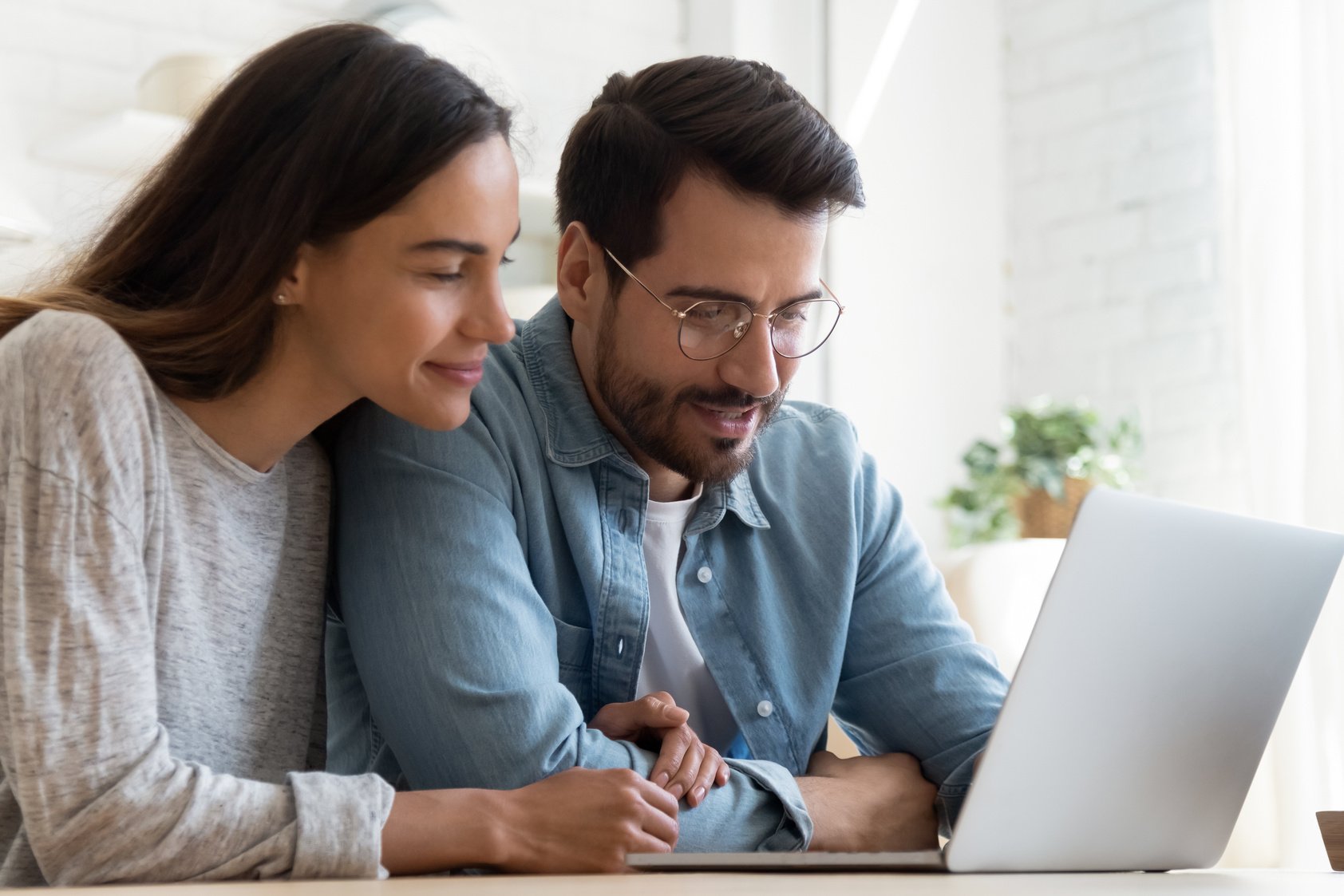 Couple looking at laptop screen watch video, read commercial offer